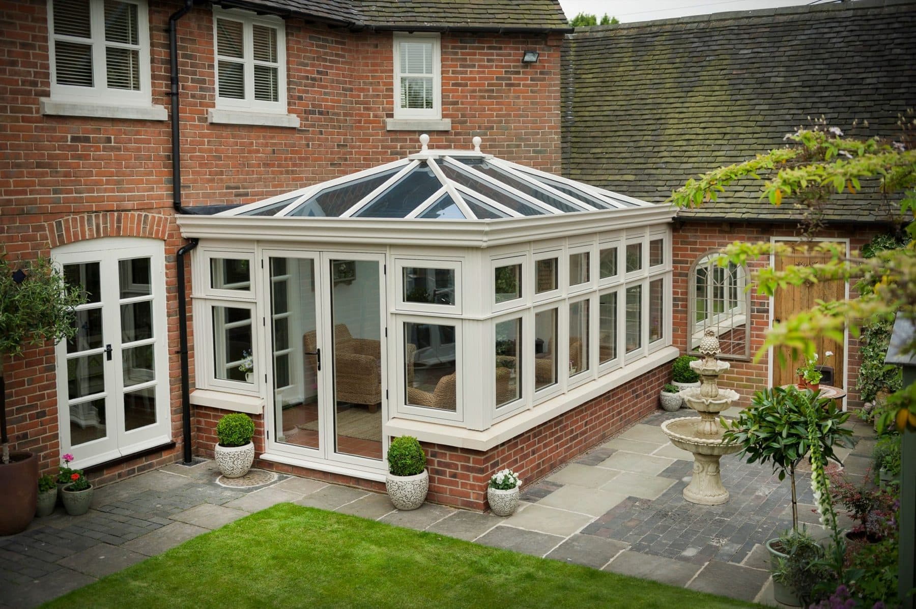 White Edwardian conservatory with glazed pyramid roof on a red brick country home