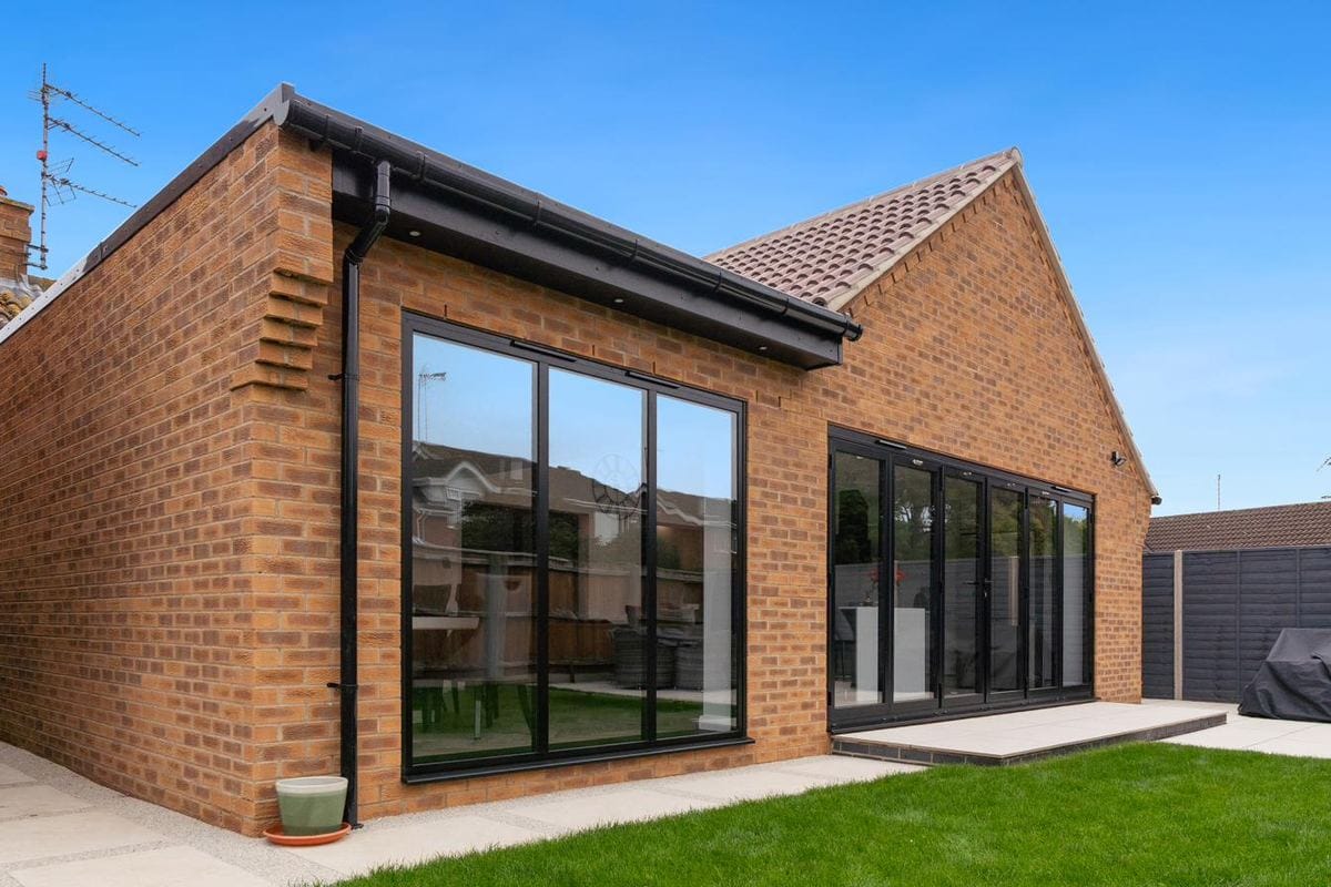 Anthracite aluminium bifold doors alongside a tall fixed picture window on a contemporary bungalow extension