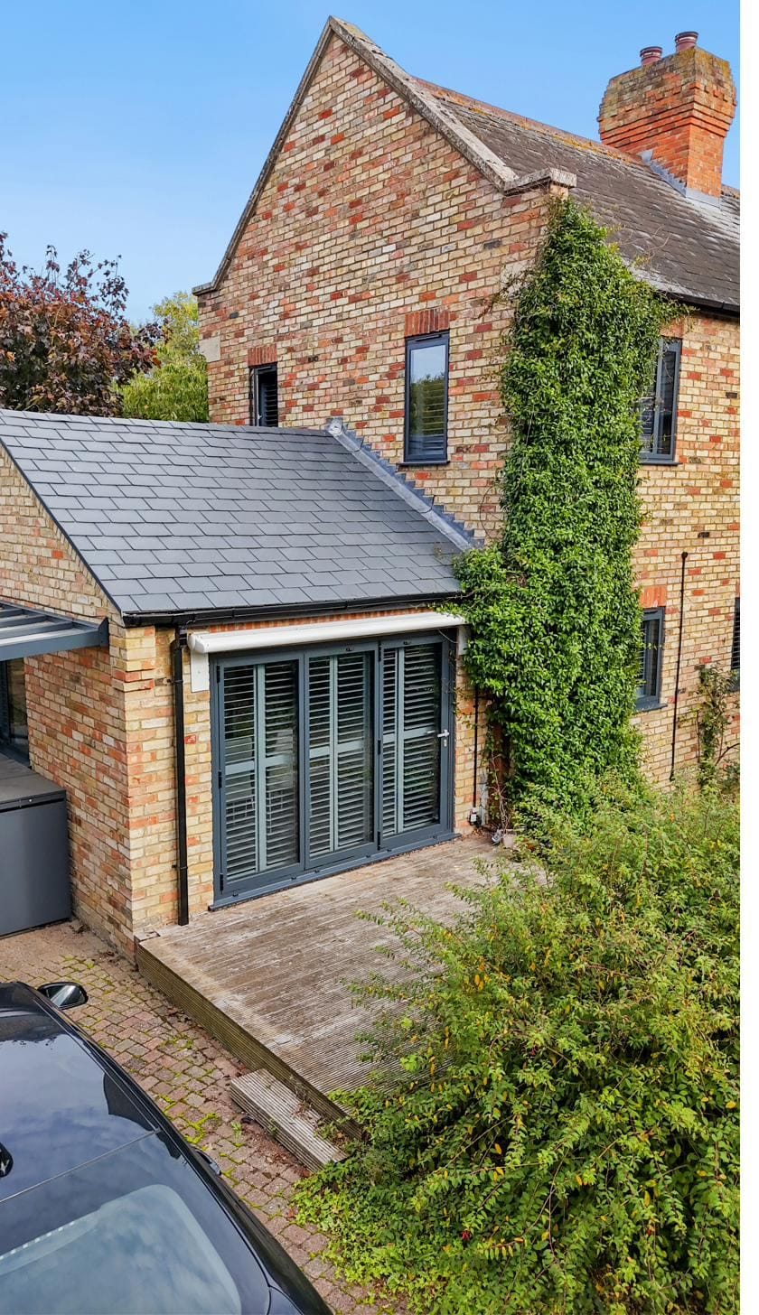 Slate-roof extension on a heritage property with three-panel bifold doors and shutters