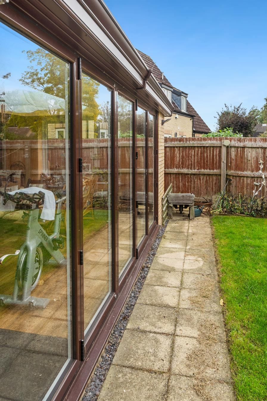 Side elevation of a brown-frame conservatory looking down the garden path
