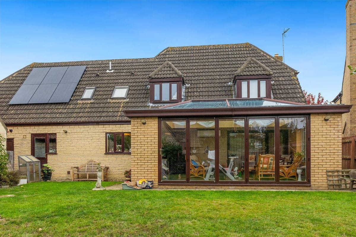 Rear view of a conservatory with twin dormer windows above and a glass roof lantern