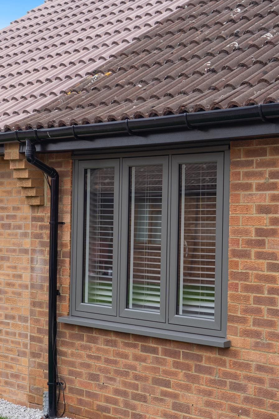 Close-up of a three-light anthracite UPVC casement window with internal blinds
