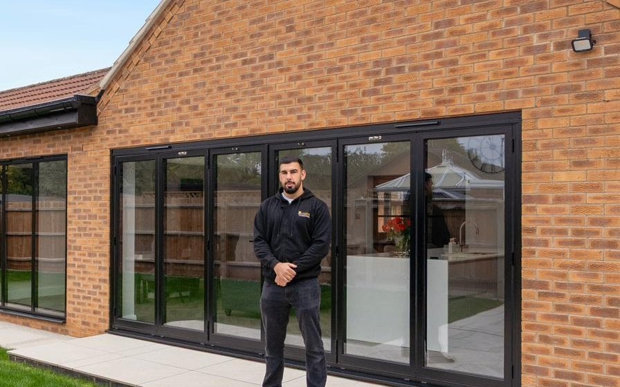Tariq from Custom Choice in front of newly-installed anthracite aluminium bifold doors on a Peterborough rear extension